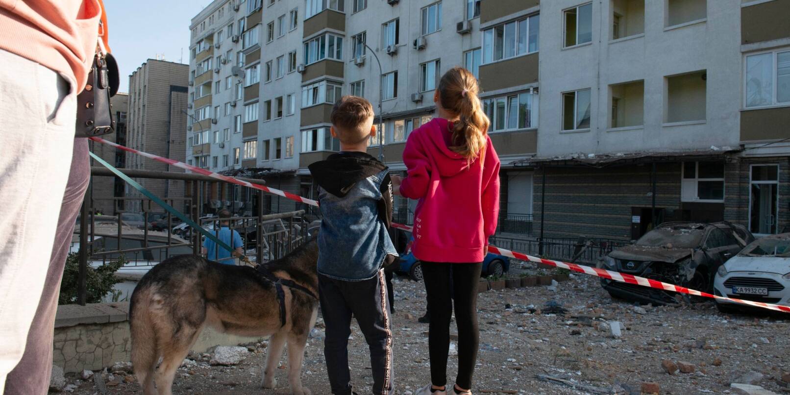 Kriegsalltag: Kinder schauen in Kiew auf ein bei russischen Raketenangriffen beschädigtes Gebäude. Kriegsalltag: Kinder schauen in Kiew auf ein bei russischen Raketenangriffen beschädigtes Gebäude.