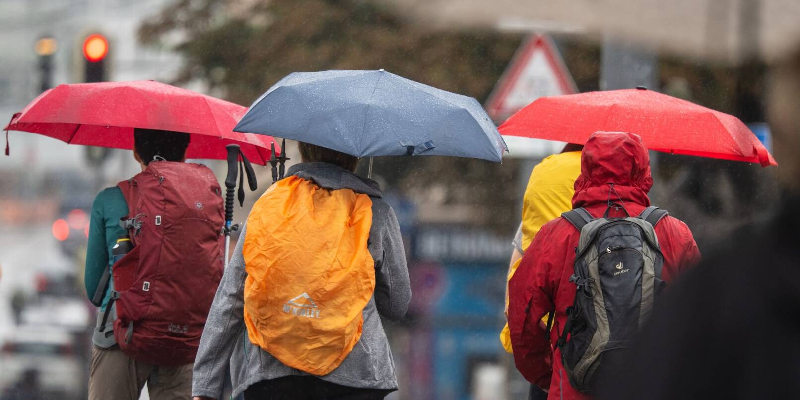 Menschen schützen sich bei Regen mit ihren Schirmen.