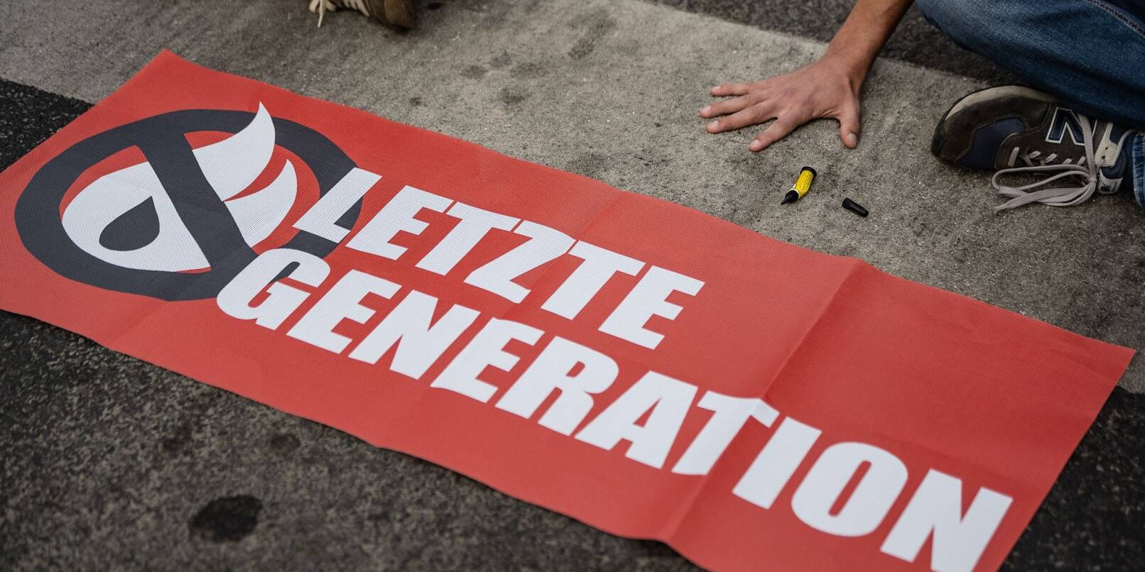 Ein Aktivist der Gruppe Letzte Generation hat seine Hand auf der Straße festgeklebt und blockiert eine Kreuzung.