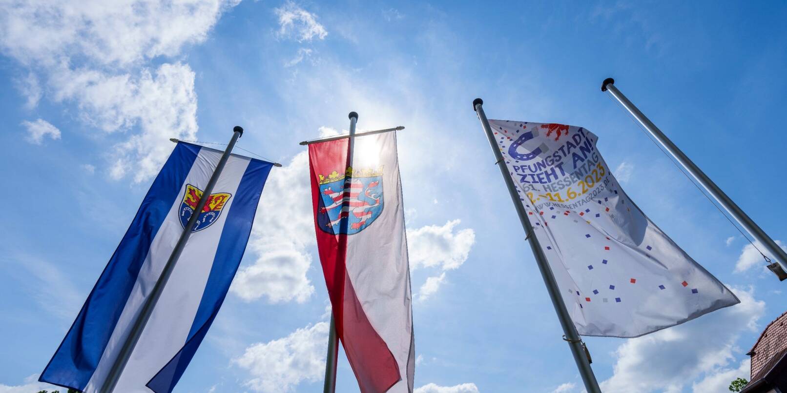 Das Wappen von Pfungstadt (l-r), der Hessen-Löwe und die «Hessentags-Flagge» wehen in der Innenstadt im Wind.