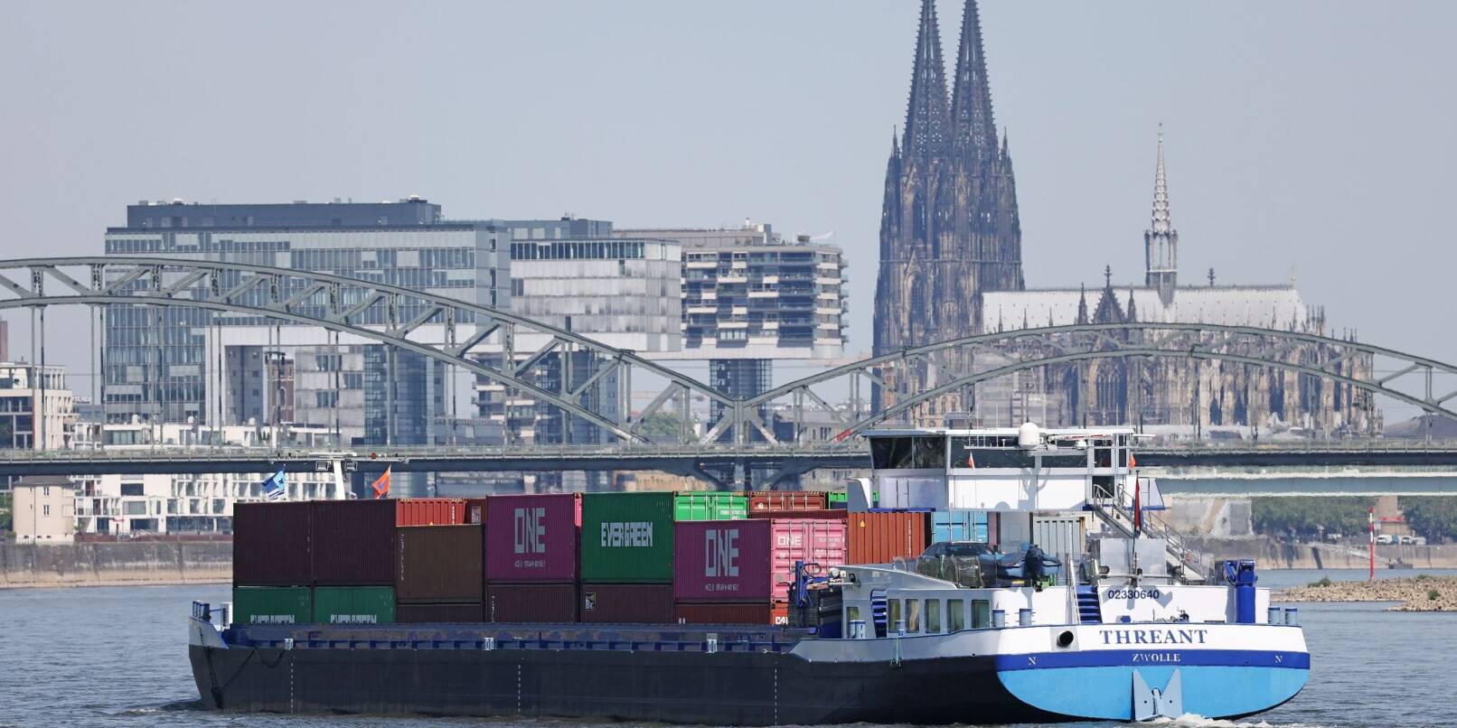 Ein mit Containern beladenes Binnenschiff über dem Rhein.