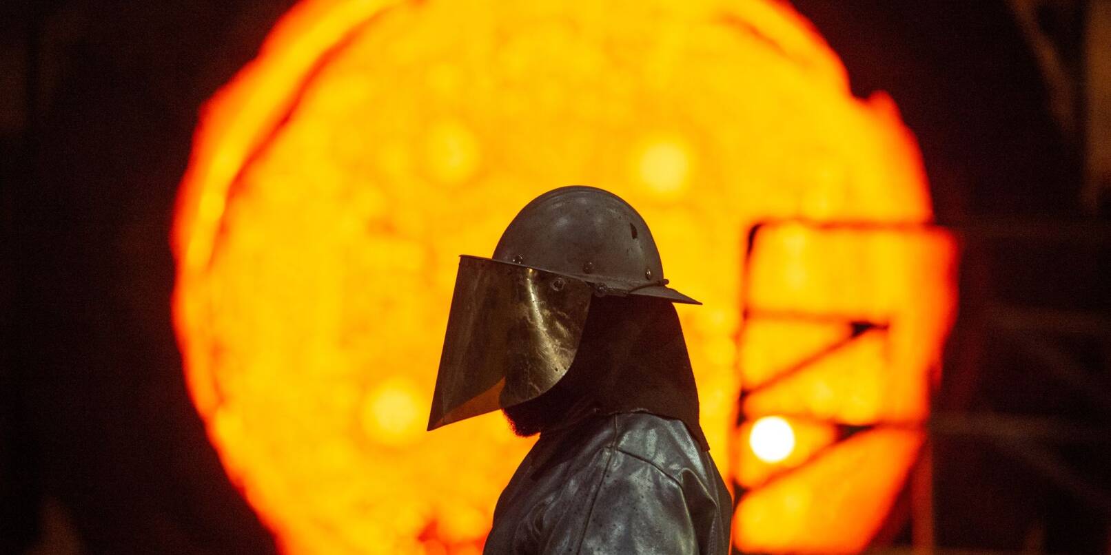 Ein Mitarbeiter steht im Stahlwerk der Salzgitter AG vor einer glühenden Roheisenpfanne.