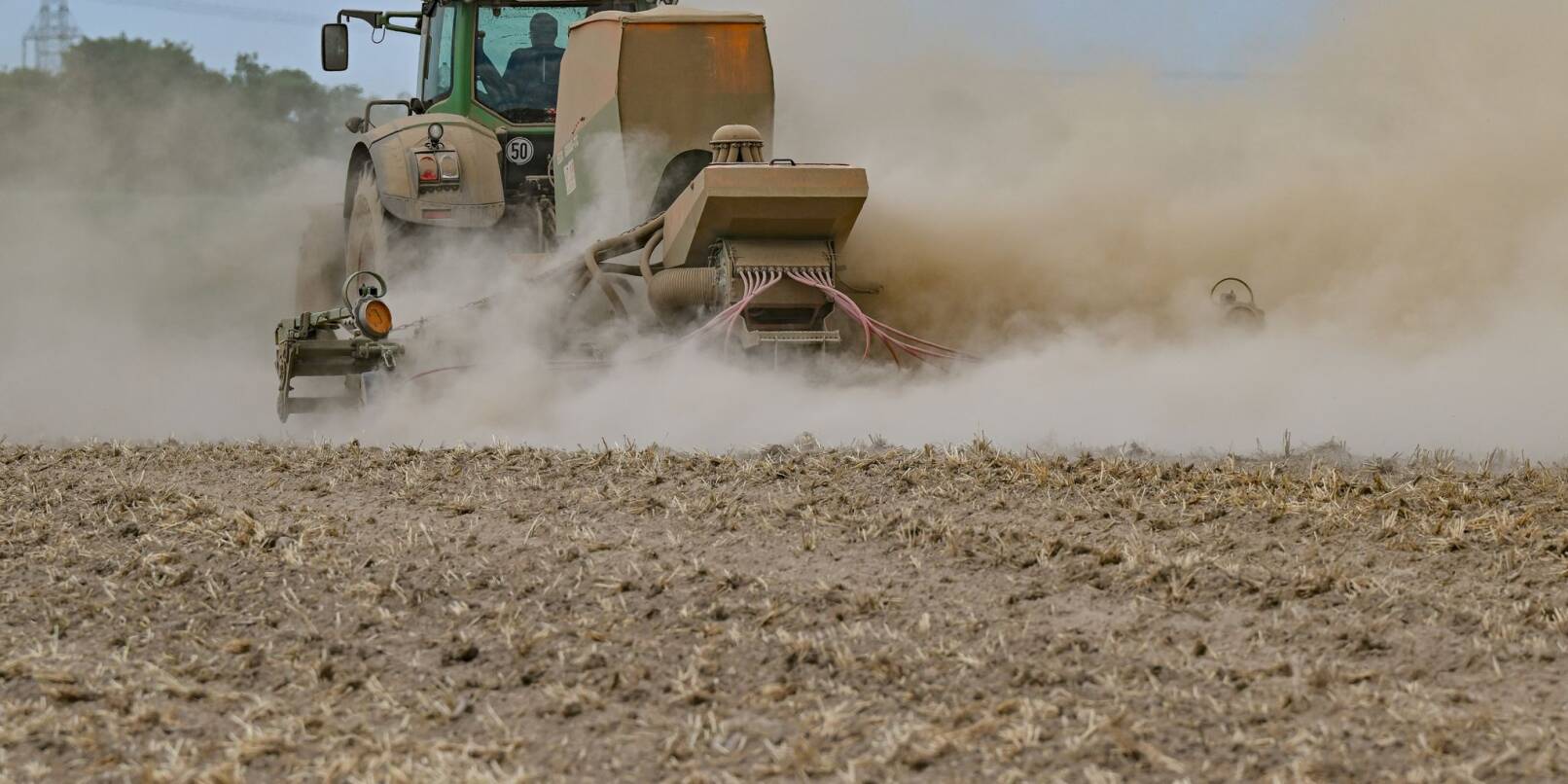 Ein Landwirt in Brandenburg drillt Saatgut in seinen ausgetrockneten Acker.