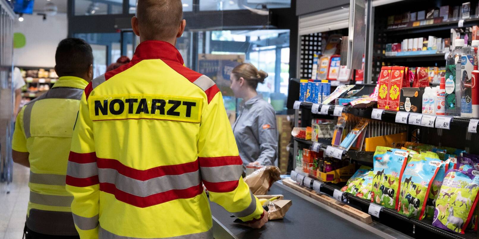 Ein Notarzt steht an einer Supermarktkasse (Gestellte Szene).