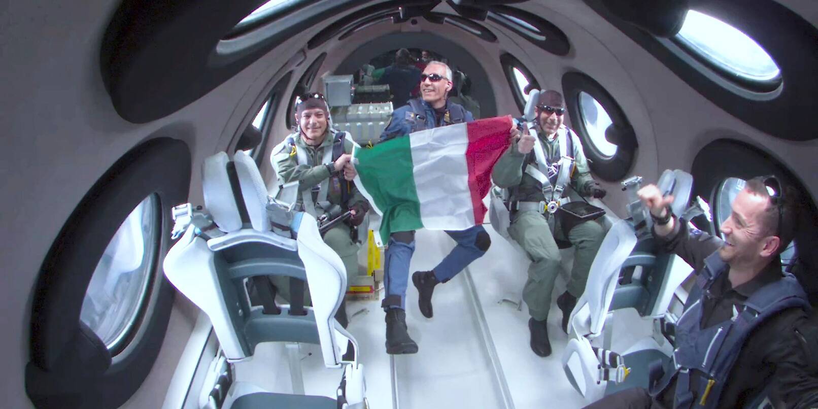 Walter Villadei (M), Wissenschaftler der italienischen Luftwaffe, hält eine italienische Fahne, während er und andere italienische Forscher einige Momente der Schwerelosigkeit an Bord des Raumflugzeugs von Virgin Galactic erleben.