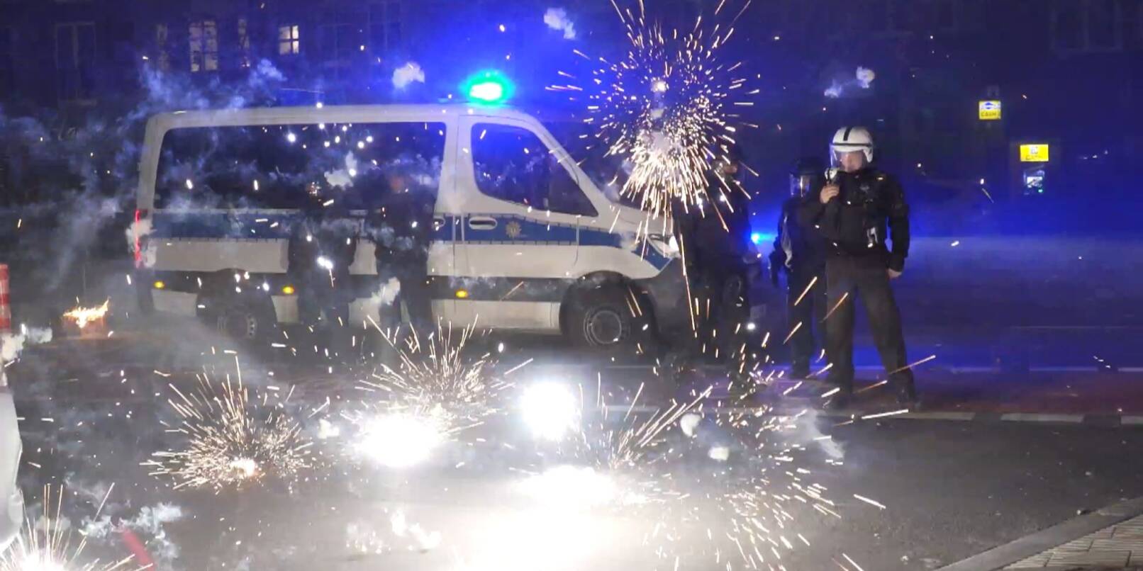 Polizeibeamte stehen in der Silvesternacht in Berlin hinter explodierendem Feuerwerk (Symbolbild). «Auch in Deutschland sind an bestimmten Orten solche Krawallexzesse denkbar», sagt Polizei-Gewerkschafter Jochen Kopelke.
