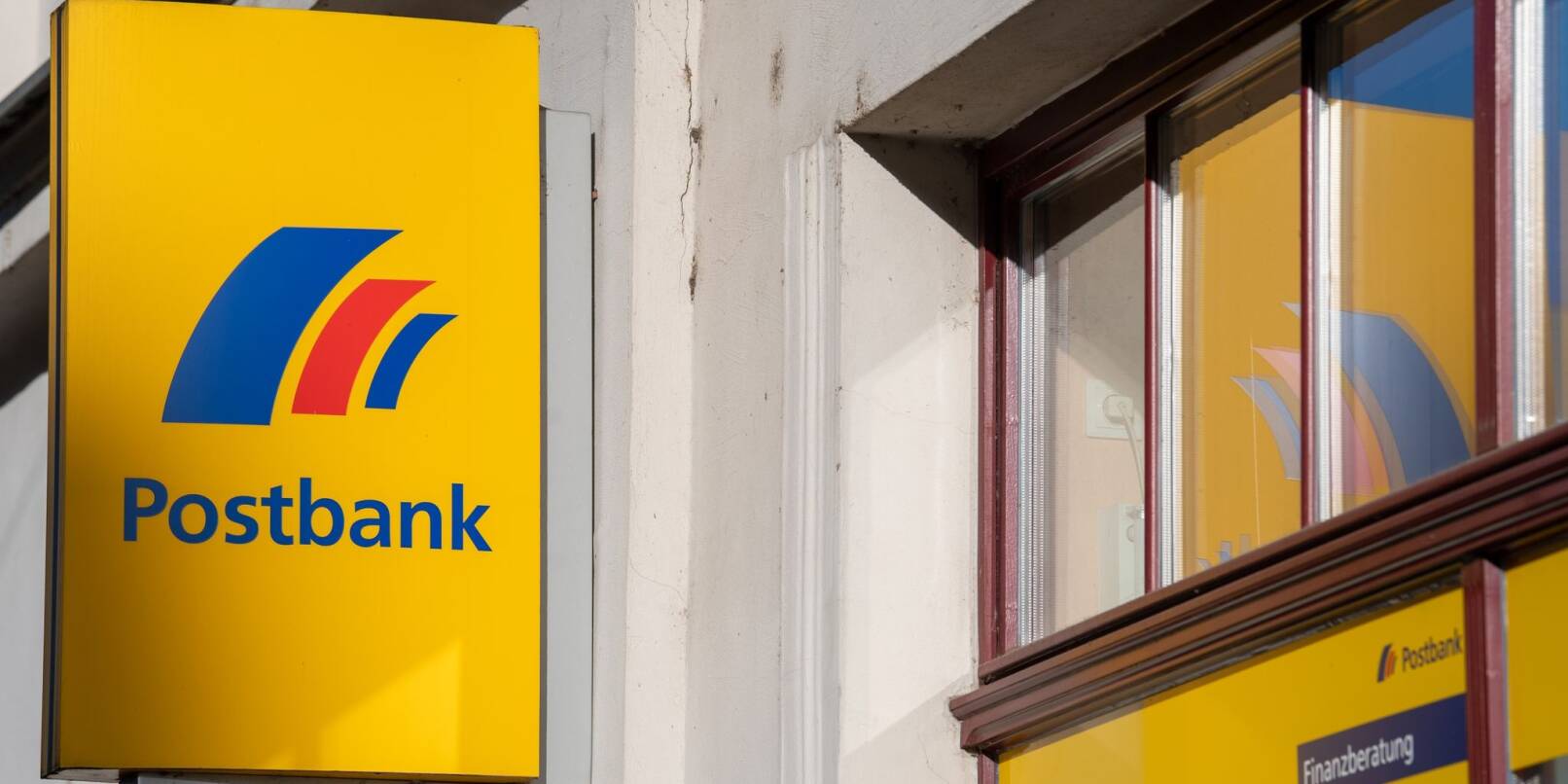 Ein Schild mit dem Logo der Postbank an der Fassade einer Bankfiliale in Brandenburg an der Havel.
