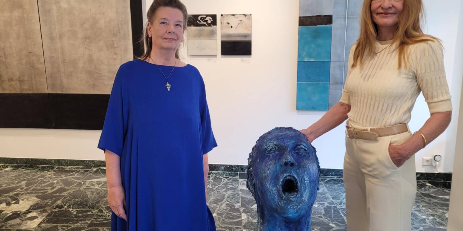 Der überlebensgroße Kopf aus Gips, dessen Mund und Augen vor Entsetzen zum Schrei aufgerissen sind, ist ein Werk von Dagmar Vogt (rechts). Daneben zeigt die Galerie Klüber Gemälde von Ulla Ströhmann (links).