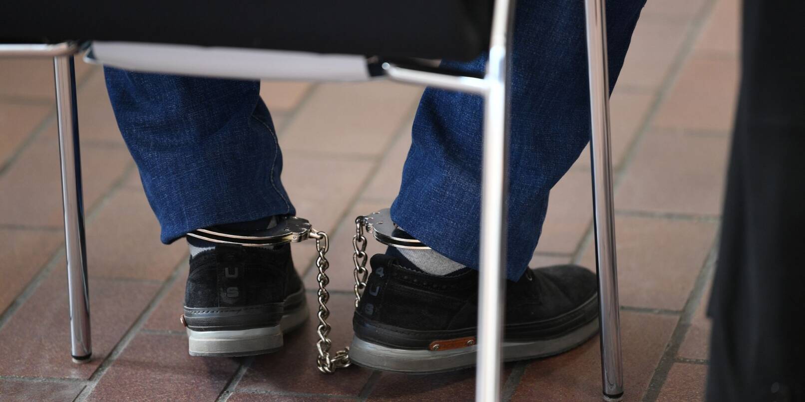 Ein Angeklagter sitzt mit Fußfesseln im Gerichtssaal auf seinem Stuhl.