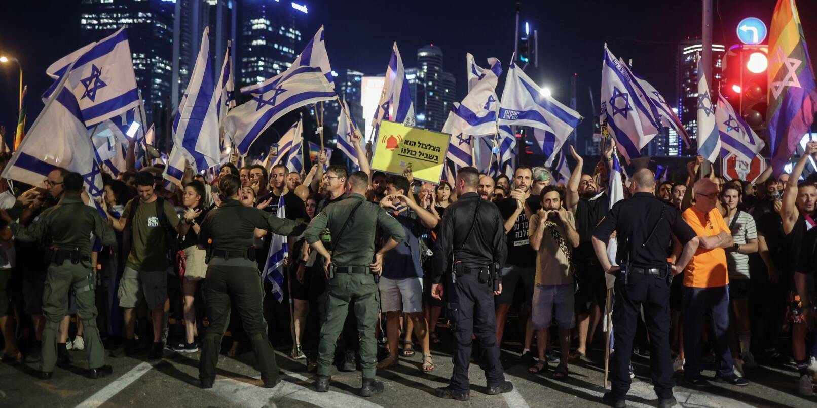Polizisten stehen vor Demonstranten während eines Protests gegen die israelische Regierung.