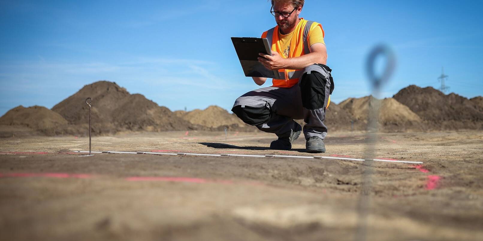 Der Archäologe Nikita Sirman vom Landesamt für Denkmalpflege und Archäologie vermisst und kartiert den mutmaßlichen Grundriss eines Grubenhauses.
