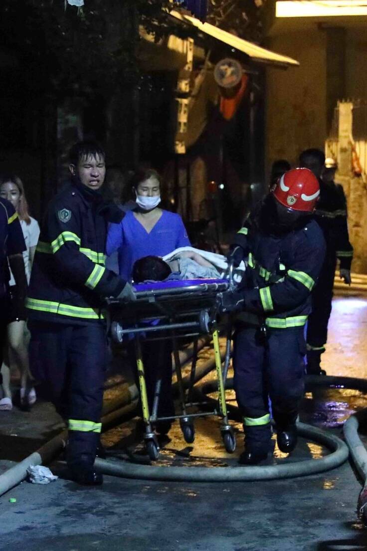 Rettungskräfte tragen eine Person aus dem brennenden Gebäude in Hanoi.