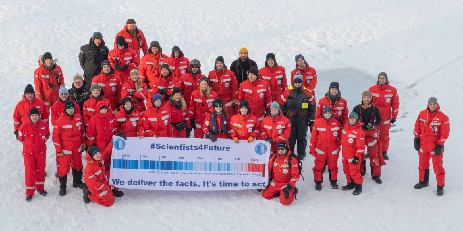 Forscher des Alfred Wegener Instituts mit einem Transparent mit der Aufschrift "#Scientists4Future - We deliver the facts. It's time to act" in der Arktis.
