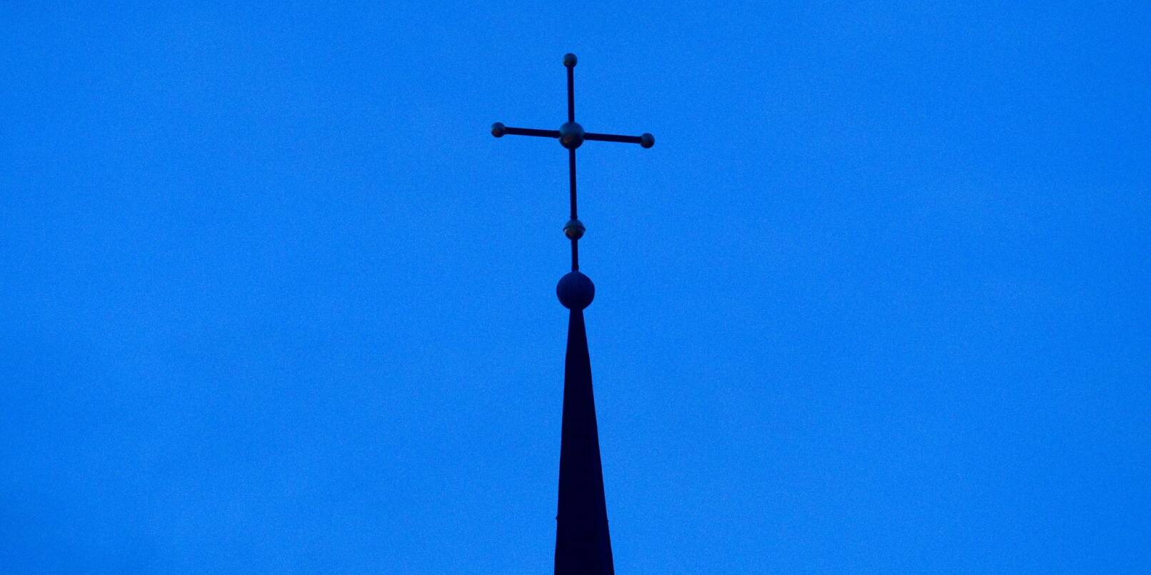 Kreuz einer evangelisch-lutherischen Kirche in der Abenddämmerung.