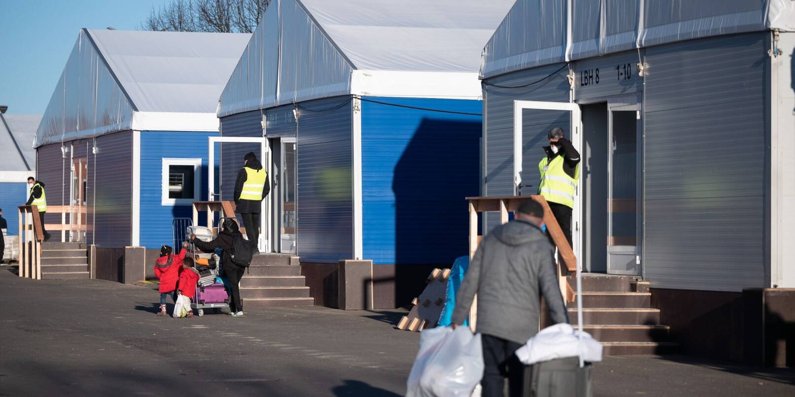 Menschen gehen an Unterkünften in der Erstaufnahmeeinrichtung des Landes Hessen für Geflüchtete in Gießen vorbei. Menschen gehen an Unterkünften in der Erstaufnahmeeinrichtung des Landes Hessen für Geflüchtete in Gießen vorbei.