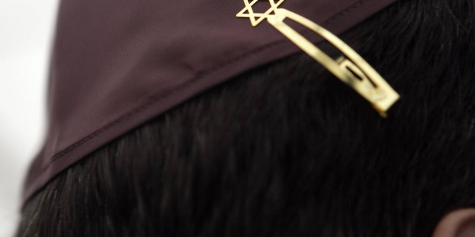 Ein Jude mit einer Kippa, die mit einer Davidstern-Klammer am Haar befestigt ist.