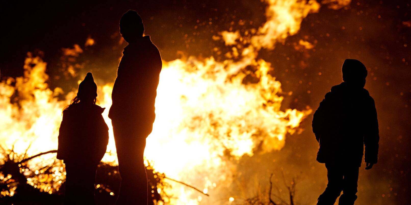 Ein Mann und zwei Kinder sind vor einem Osterfeuer zu sehen.