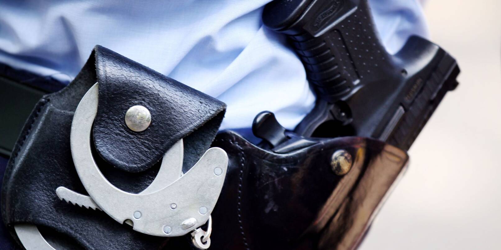 Ein Polizist mit Handschellen und Pistole am Gürtel.