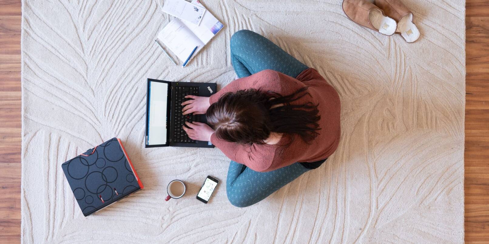 Eine Frau sitzt im Wohnzimmer am Laptop. Eine Frau sitzt im Wohnzimmer am Laptop.