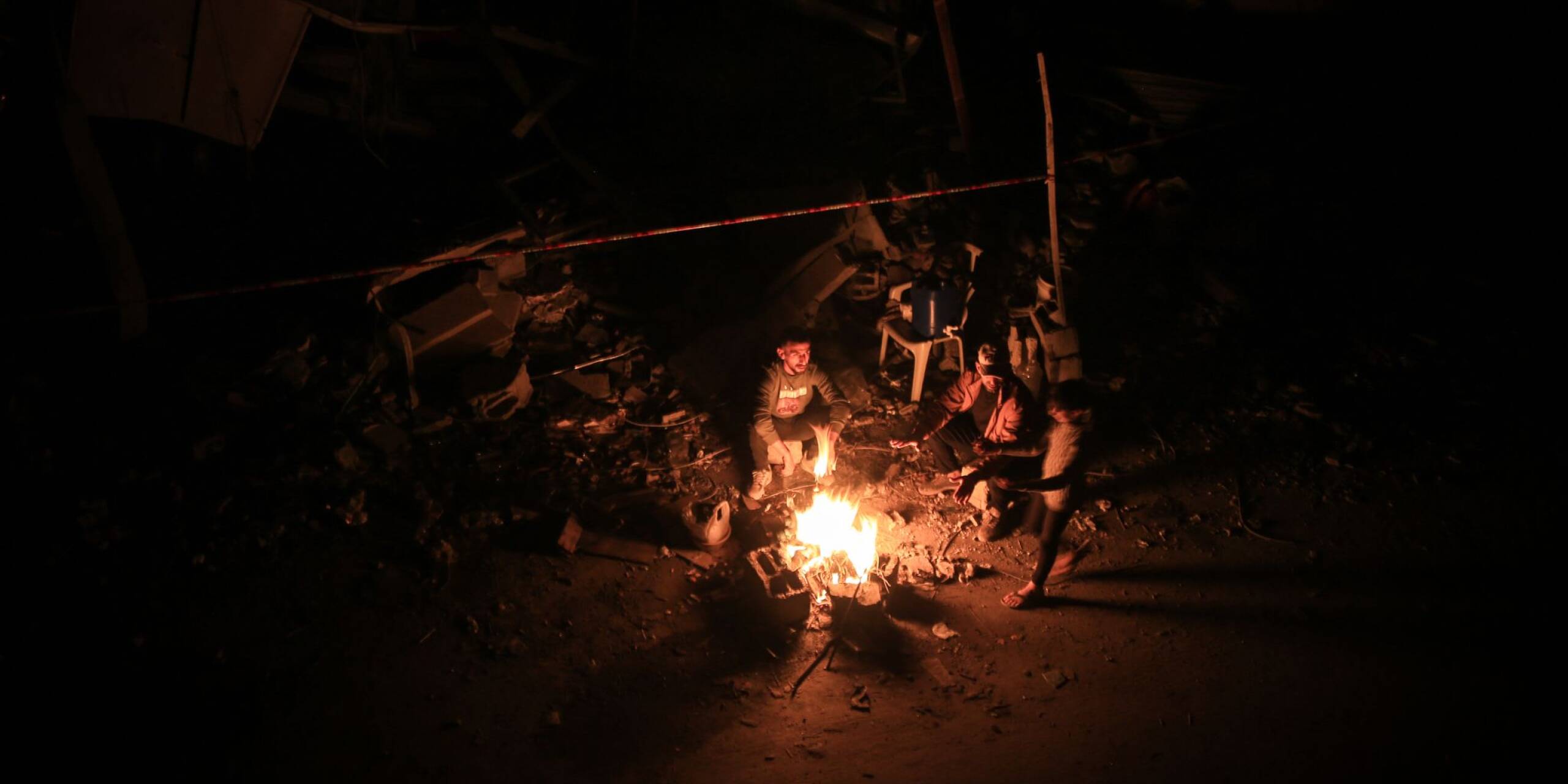 Bewohner und Bewohnerinnen von Chan Junis im südlichen Gazastreifen wärmen sich während der vorübergehenden Kampfpause zwischen Israel und der Hamas an einem Feuer.