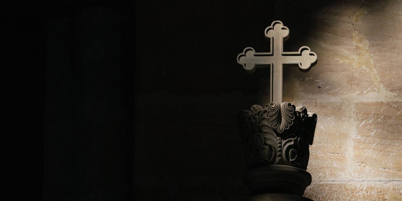 Ein Lichtstrahl fällt in einer Kirche auf ein Kreuz.