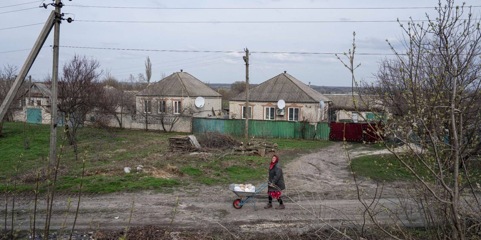 Eine Frau transportiert in Lyman im umkämpften Osten der Ukraine Hilfsgüter auf einer Schubkarre.