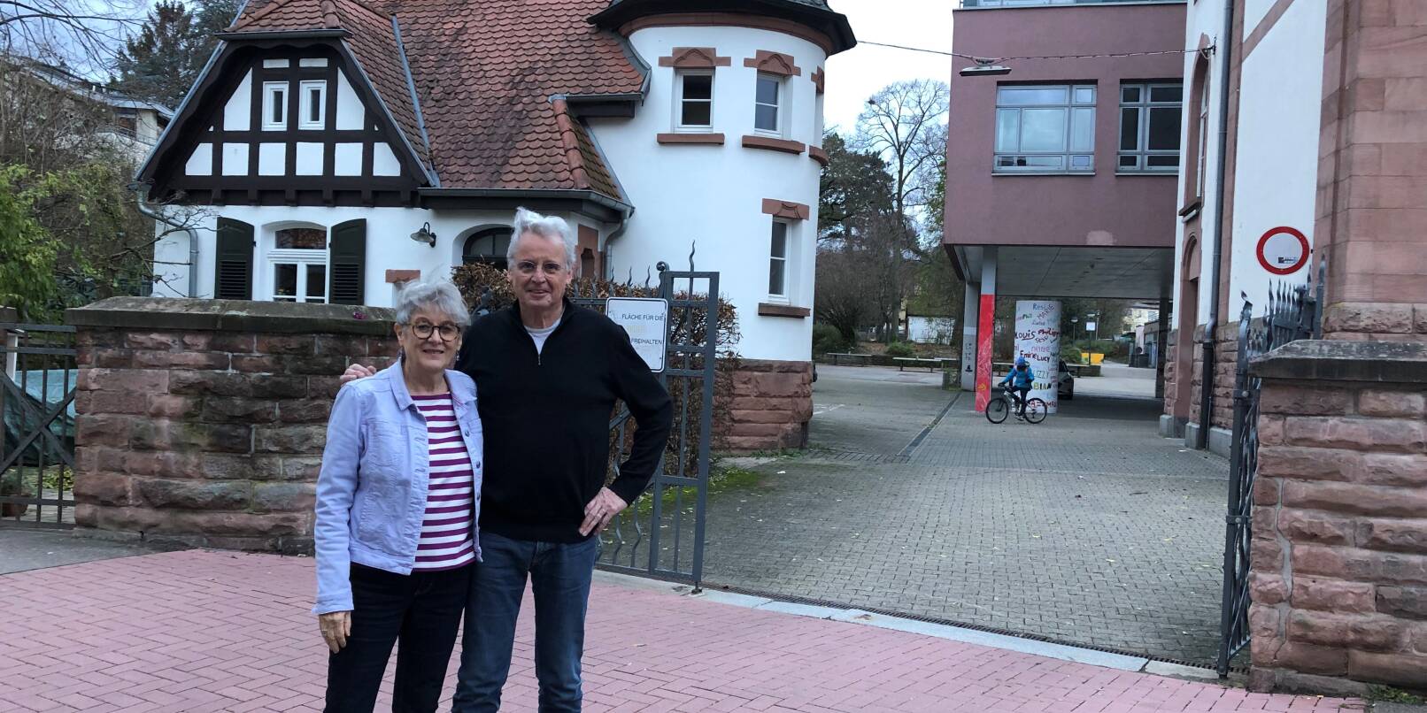 Sabine und Wolfgang Casper vor dem ehemaligen Hausmeisterhäuschen am Werner-Heisenberg-Gymnasium. Links von ihrem Heim könnte eine Flüchtlingsunterkunft gebaut werden – falls der Gemeinderat zustimmt.
