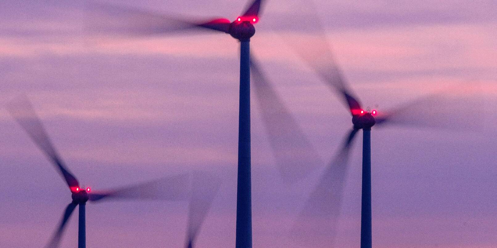 Mit Signallampen beleuchtete Windräder drehen sich nach Sonnenuntergang.