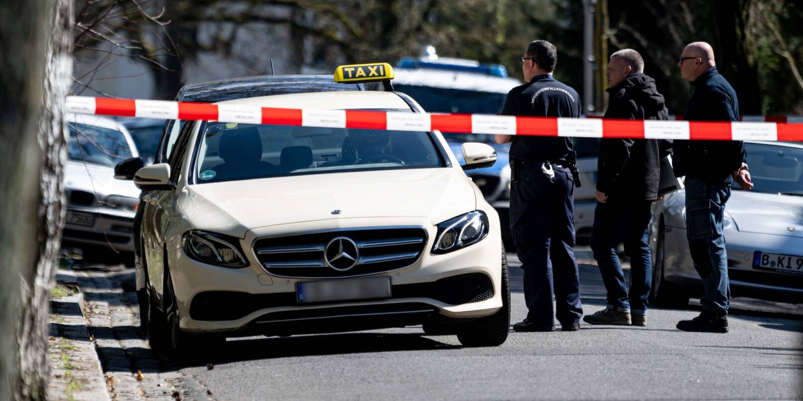 Mitarbeiter der Berliner Polizei stehen vor einem Taxi in Berlin-Grunewald. Am Donnerstagmorgen gab es dort einen tätlichen Angriff auf den Taxifahrer.