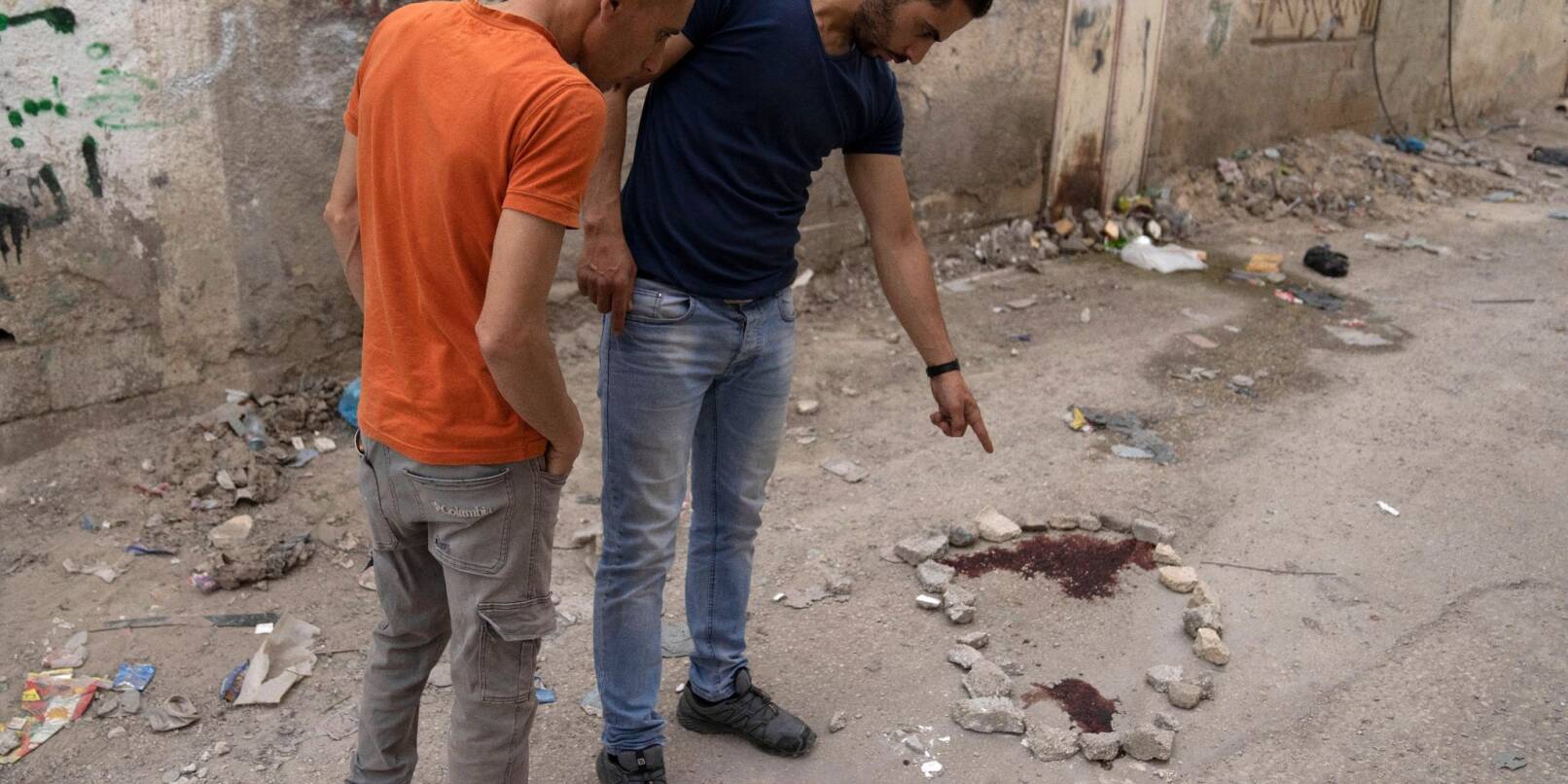Palästinenser zeigen auf einen Blutfleck auf dem Boden.