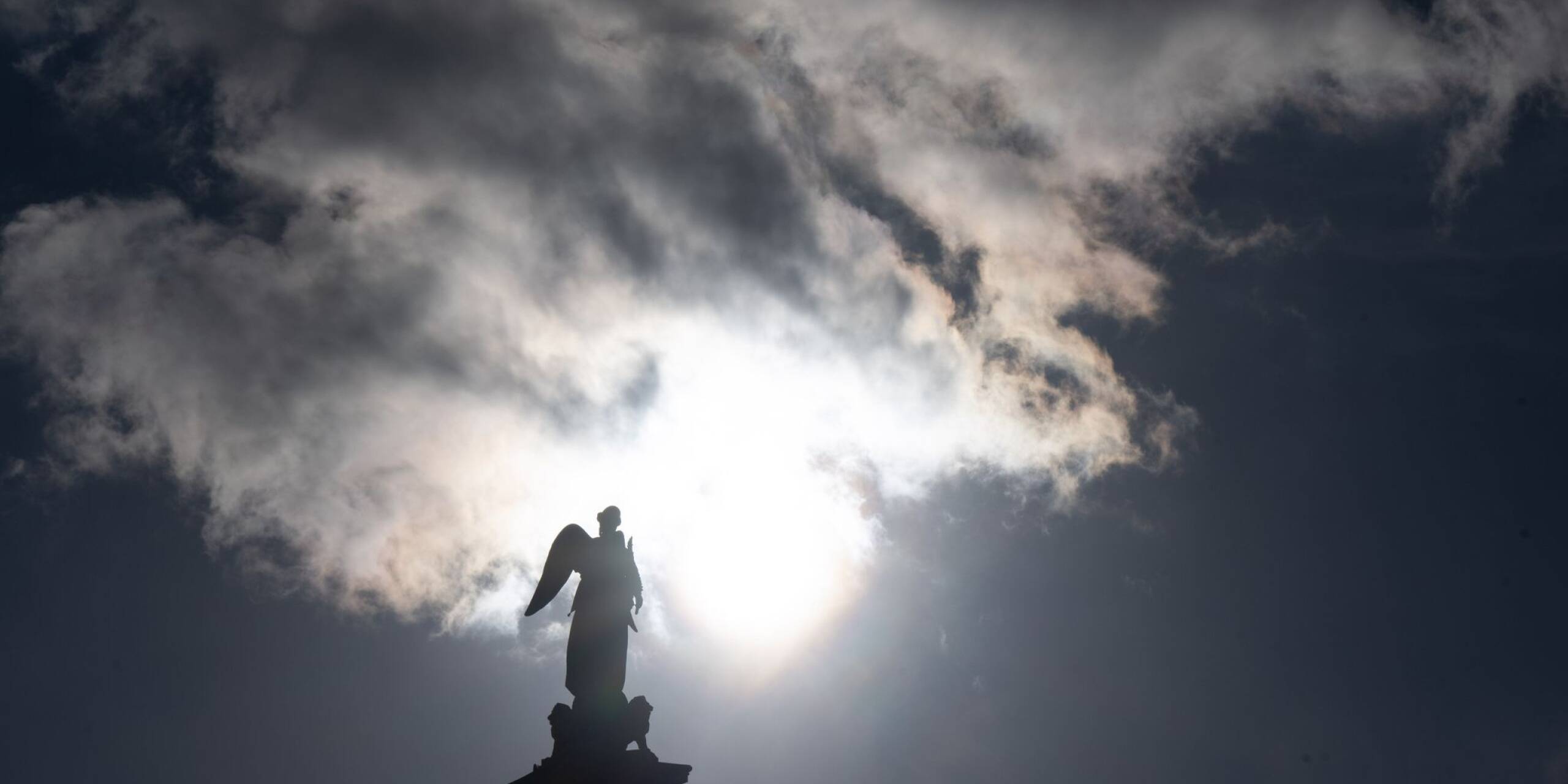 Ein Mix aus blauem Himmel, Sonne und Wolken zeigt sich über der Jubiläumssäule mit der Concordia-Statue in Stuttgart.
