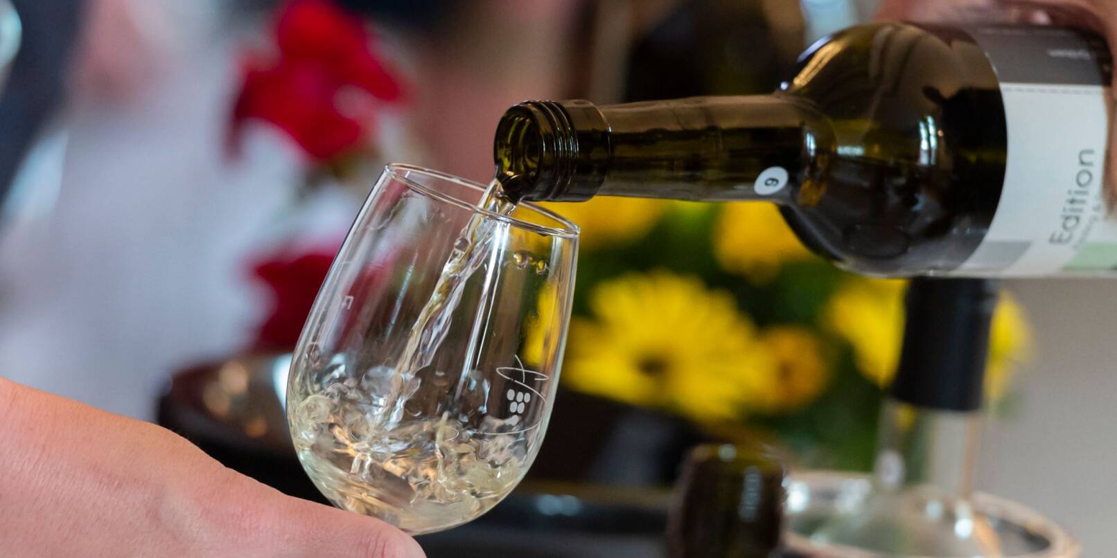 Ein Weinglas wird mit Weißwein befüllt.