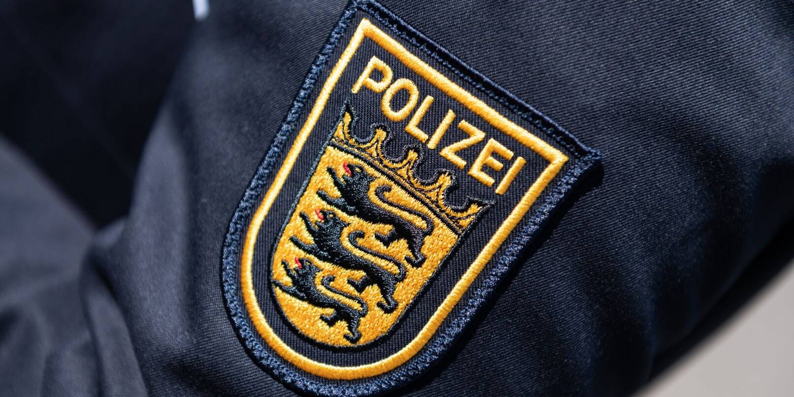 Das Wappen der Polizei Baden-Württemberg ist auf der Uniform einer Polizeibeamtin zu sehen.