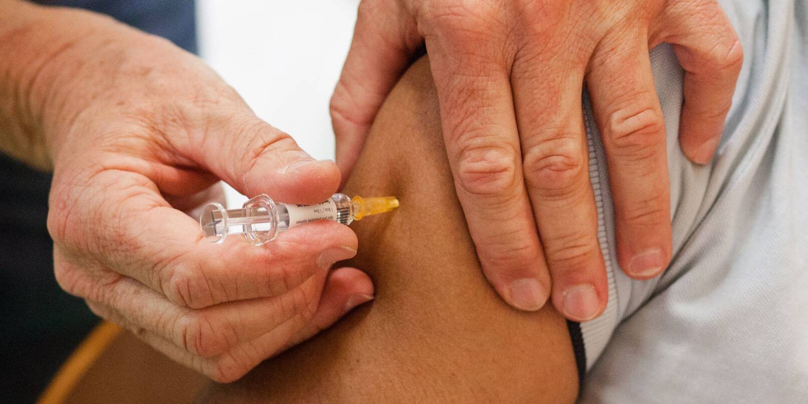 Ein Mann erhält eine Impfung gegen Grippe, Tetanus, Diphtherie, Keuchhusten (Pertussis) und Polio.