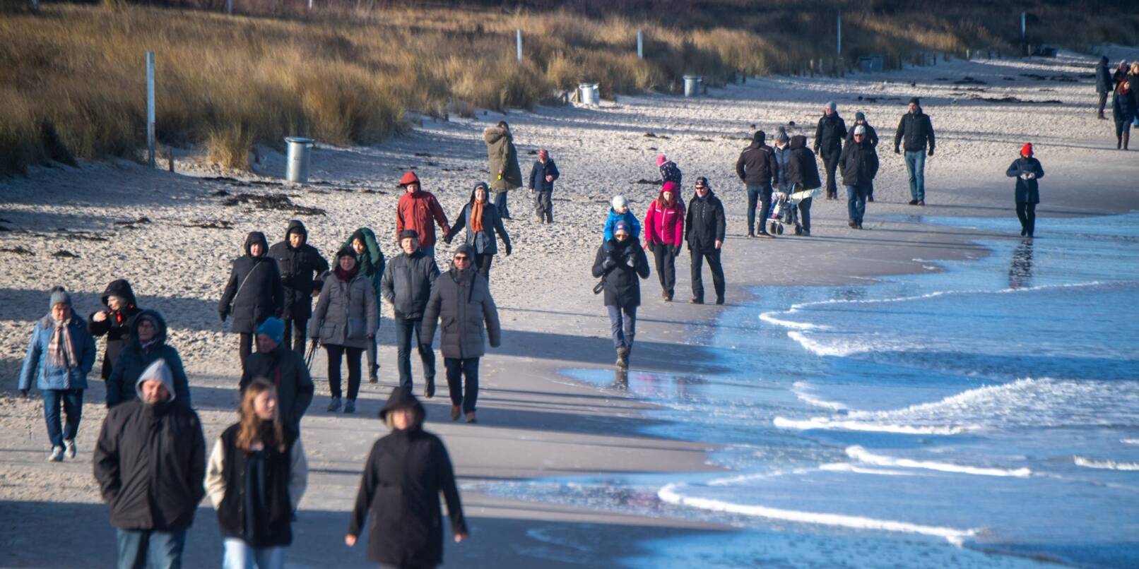 Touristen flanieren spazieren am Strand des Ostseebades auf der Insel Rügen.