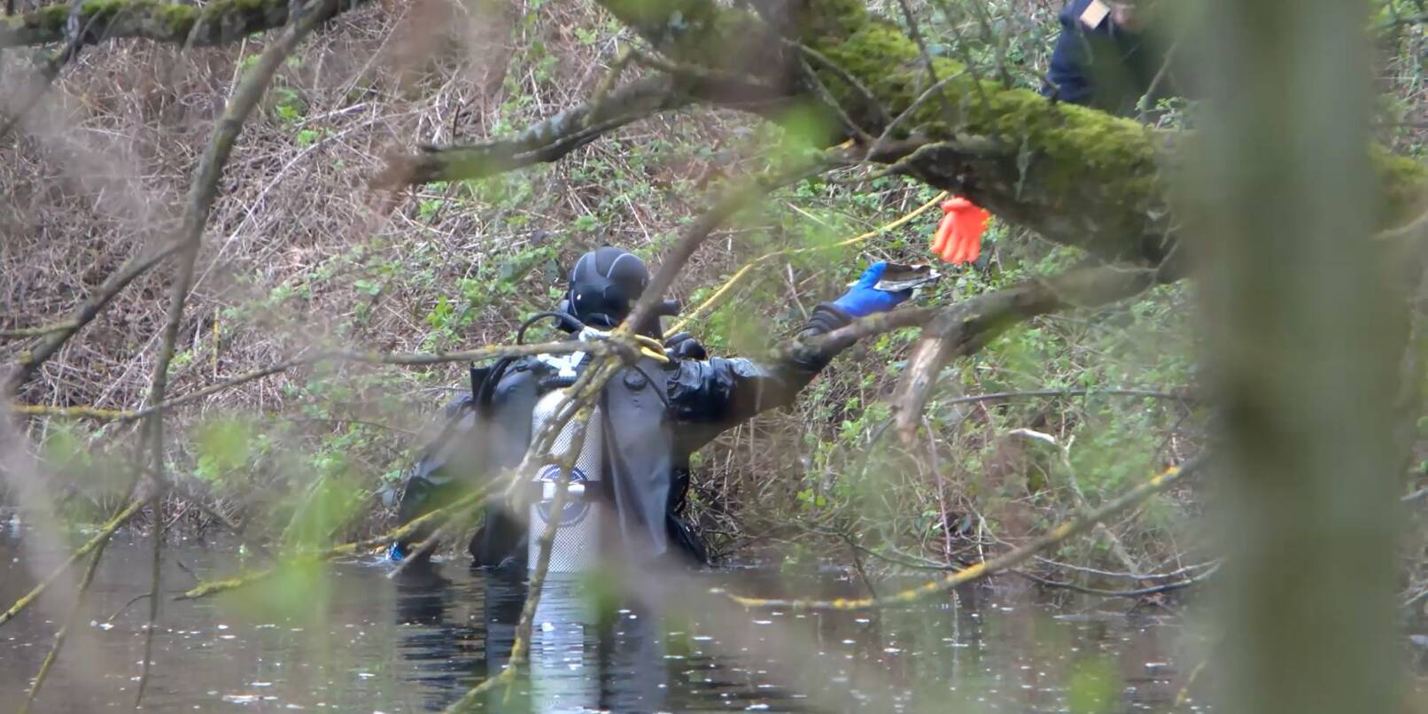 Ein Taucher der Polizei sucht in einem Gewässer nach der Leiche einer mutmaßlich getöteten Frau.