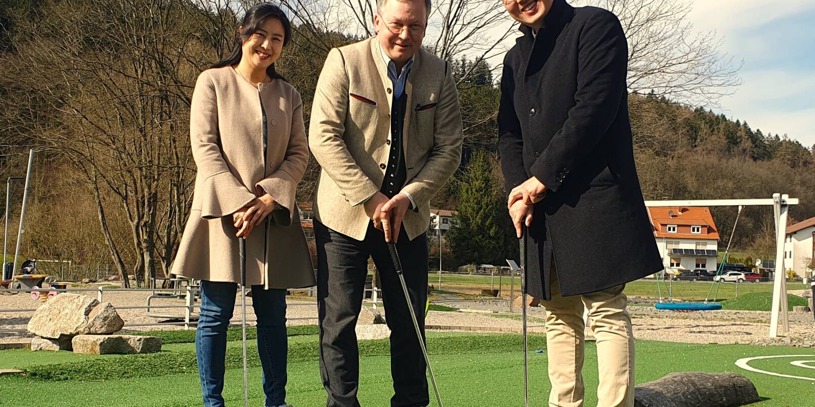 Sangmi Yoo (links) und ihr Ehemann Junchul Ye (rechts) mit Grasellenbachs Bürgermeister Makus Röth beim Spielgolf. Künftig werden die beiden koreanischen Künstler den dortigen Kiosk leiten.