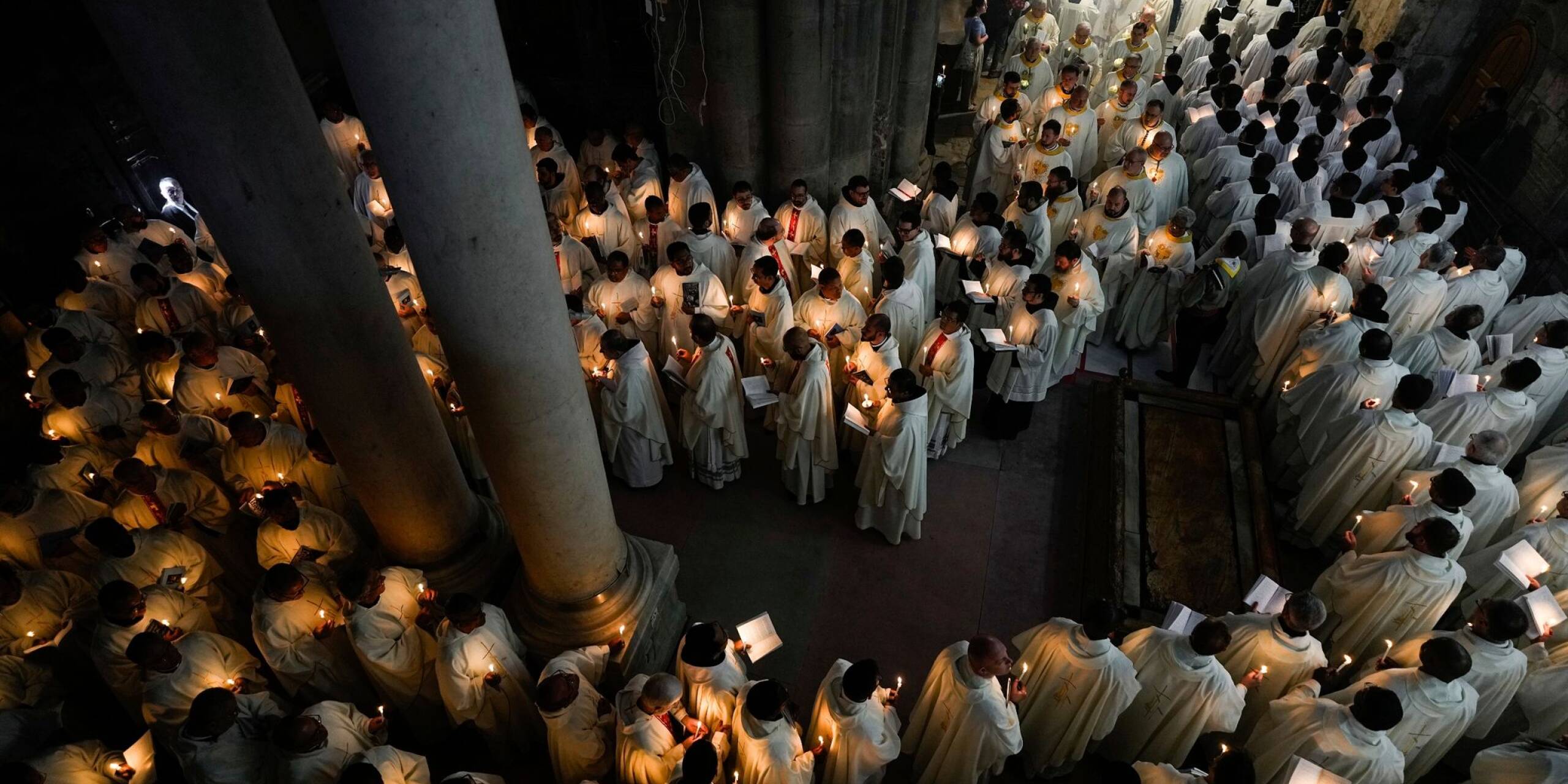 Katholische Geistliche halten Kerzen, während sie während der Prozession am Gründonnerstag zur Fußwaschung in der Grabeskirche in Jerusalem gehen.