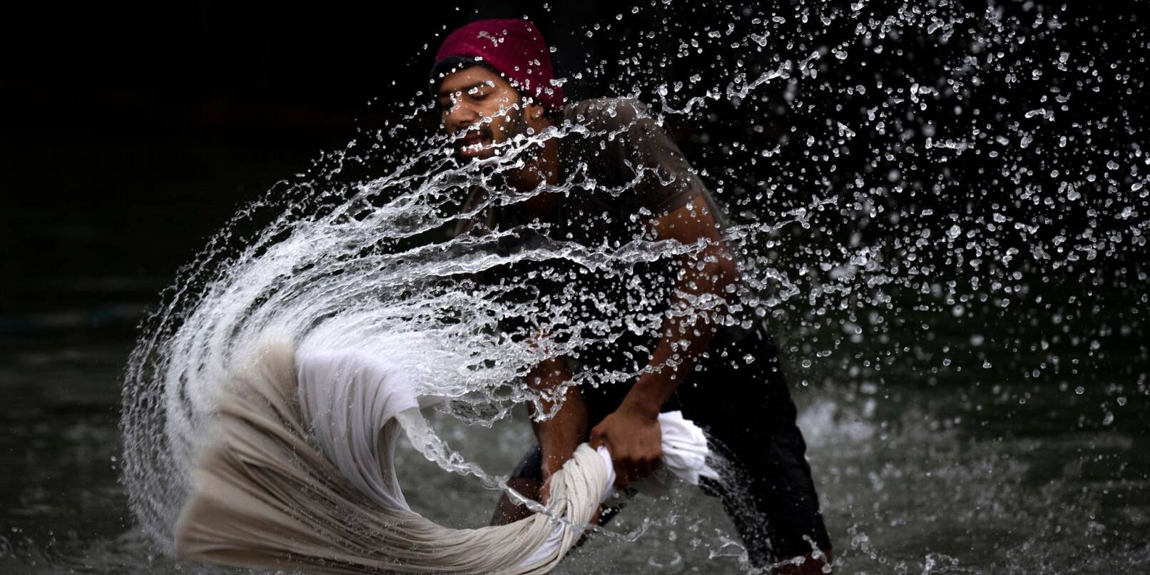 Ein Mann wäscht Textilien am Ufer des Brahmaputra-Flusses in Indien.