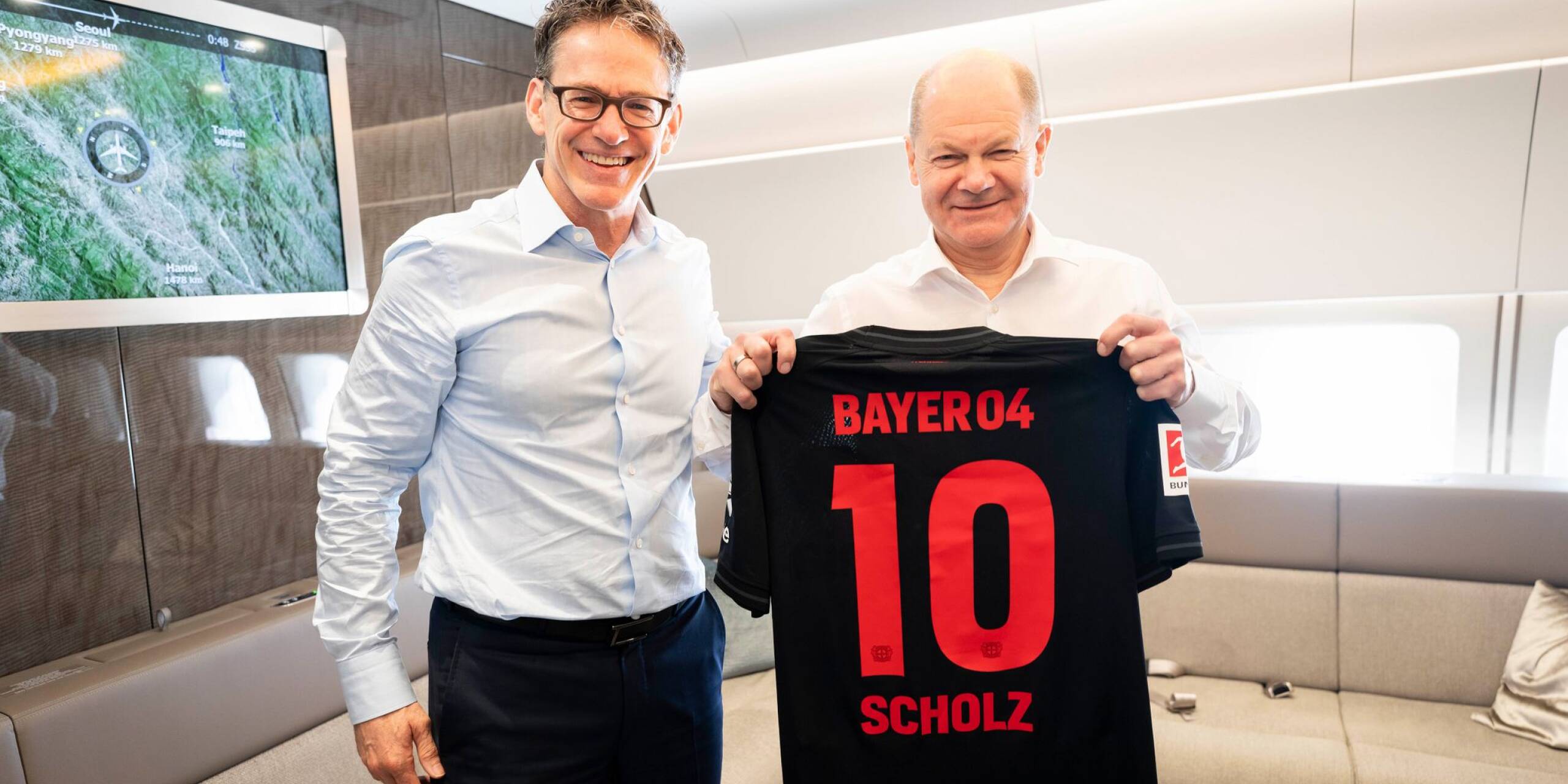 Bayer-CEO Bill Anderson (l.) überreicht Bundeskanzler Olaf Scholz (SPD) ein signiertes Trikot des neuen Bundesliga-Meisters Bayer Leverkusen.