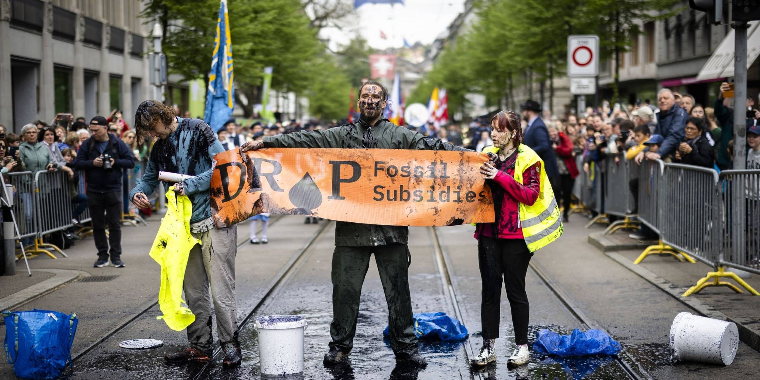 Aktivisten protestieren während des traditionellen Umzugs der Zünfte beim Sechseläuten in Zürich gegen Subventionen für fossile Brennstoffe. Um ihre Botschaft zu verdeutlichen, begießen sie sich mit einer schwarzen Flüssigkeit.