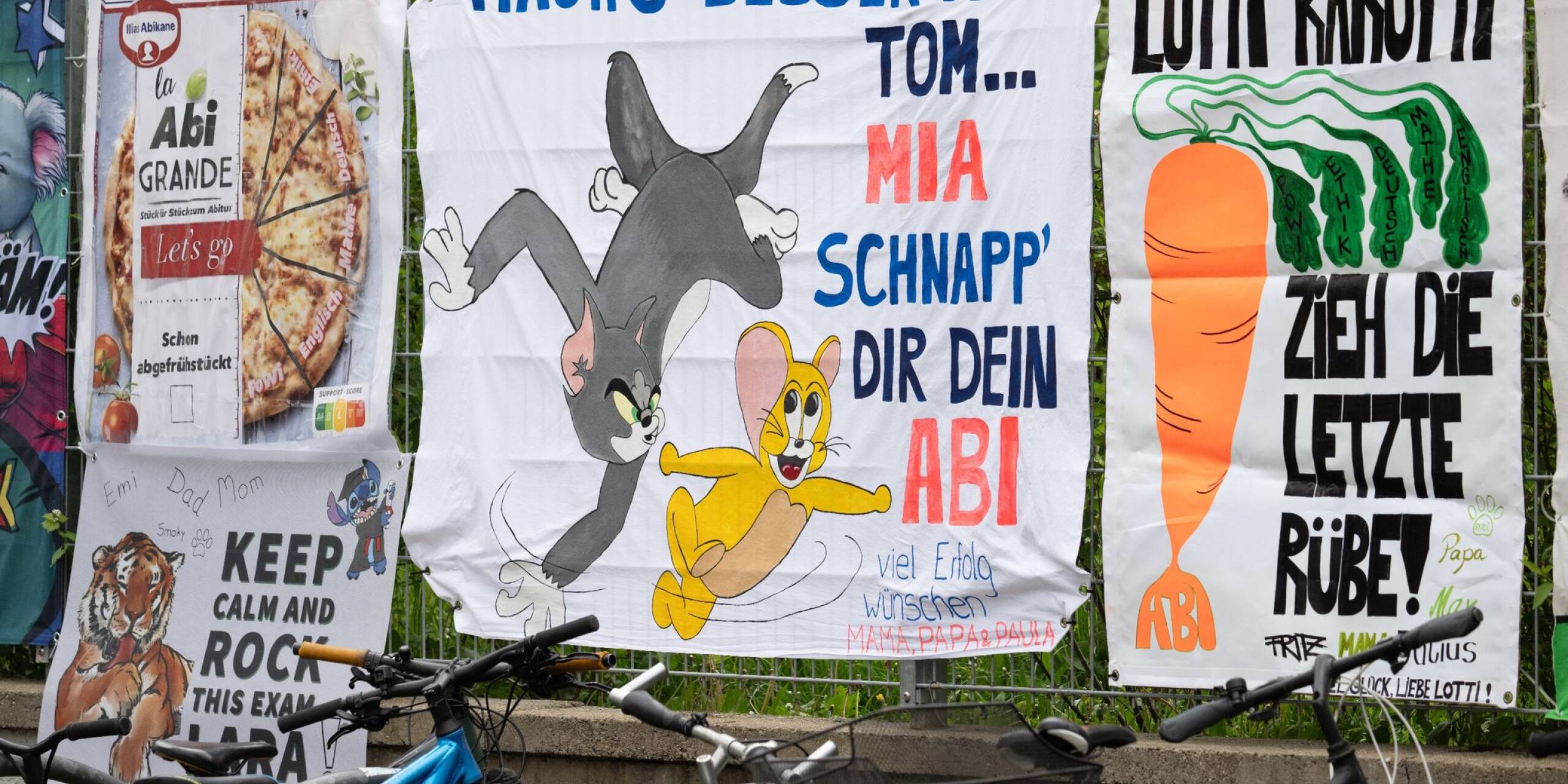 Von Freunden und Eltern gestaltete «Abi-Plakate» hängen am Zaun eines Gymnasiums in Frankfurt. In Hessen starten die schriftlichen Abiturprüfungen.