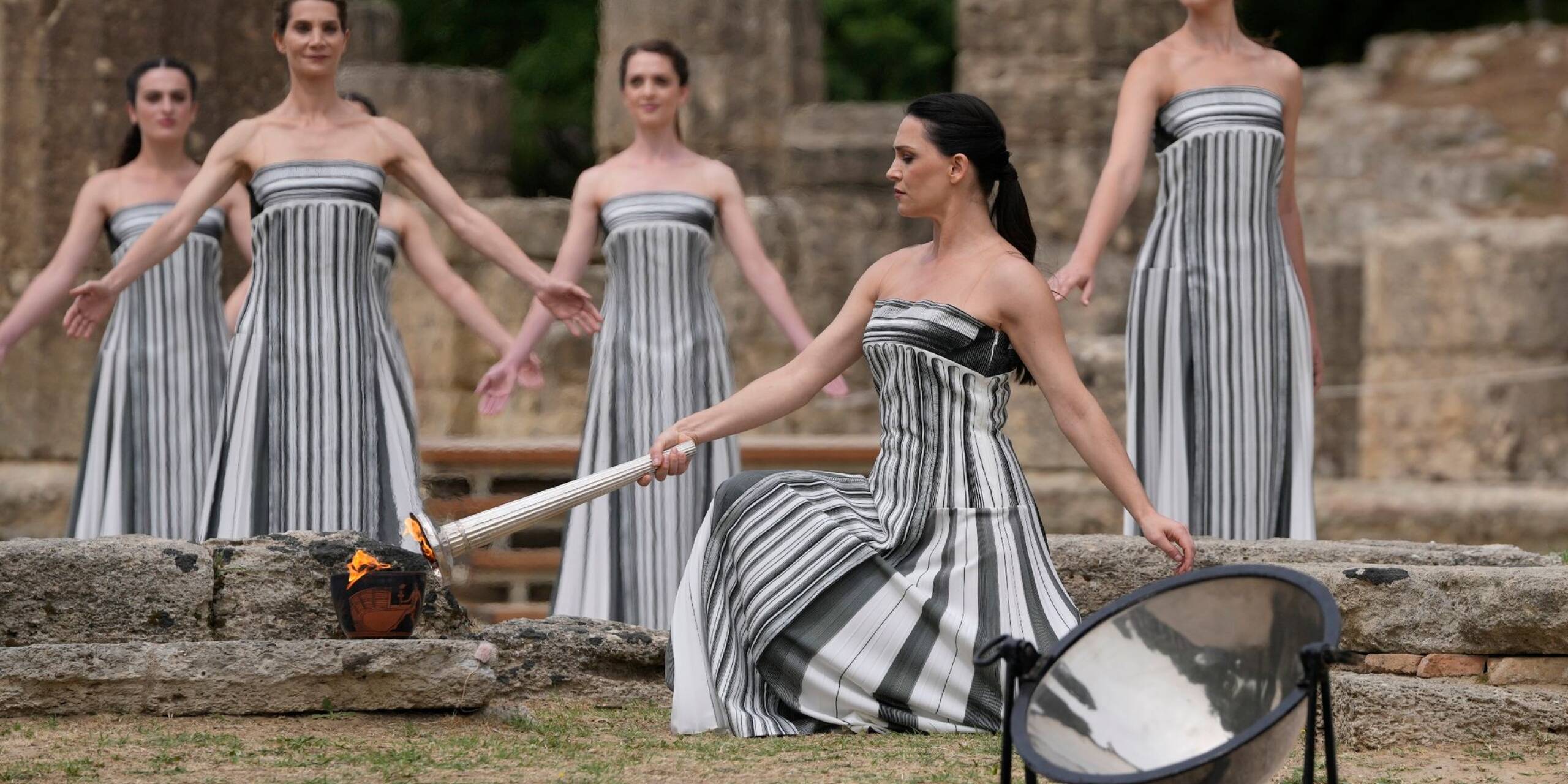 Die Schauspielerin Mary Mina (2.v.r.), die eine Hohepriesterin spielt, entzündet eine Fackel während der offiziellen Zeremonie zur Entzündung der Flamme für die Olympischen Spiele in Paris auf dem Gelände des antiken Olympia.