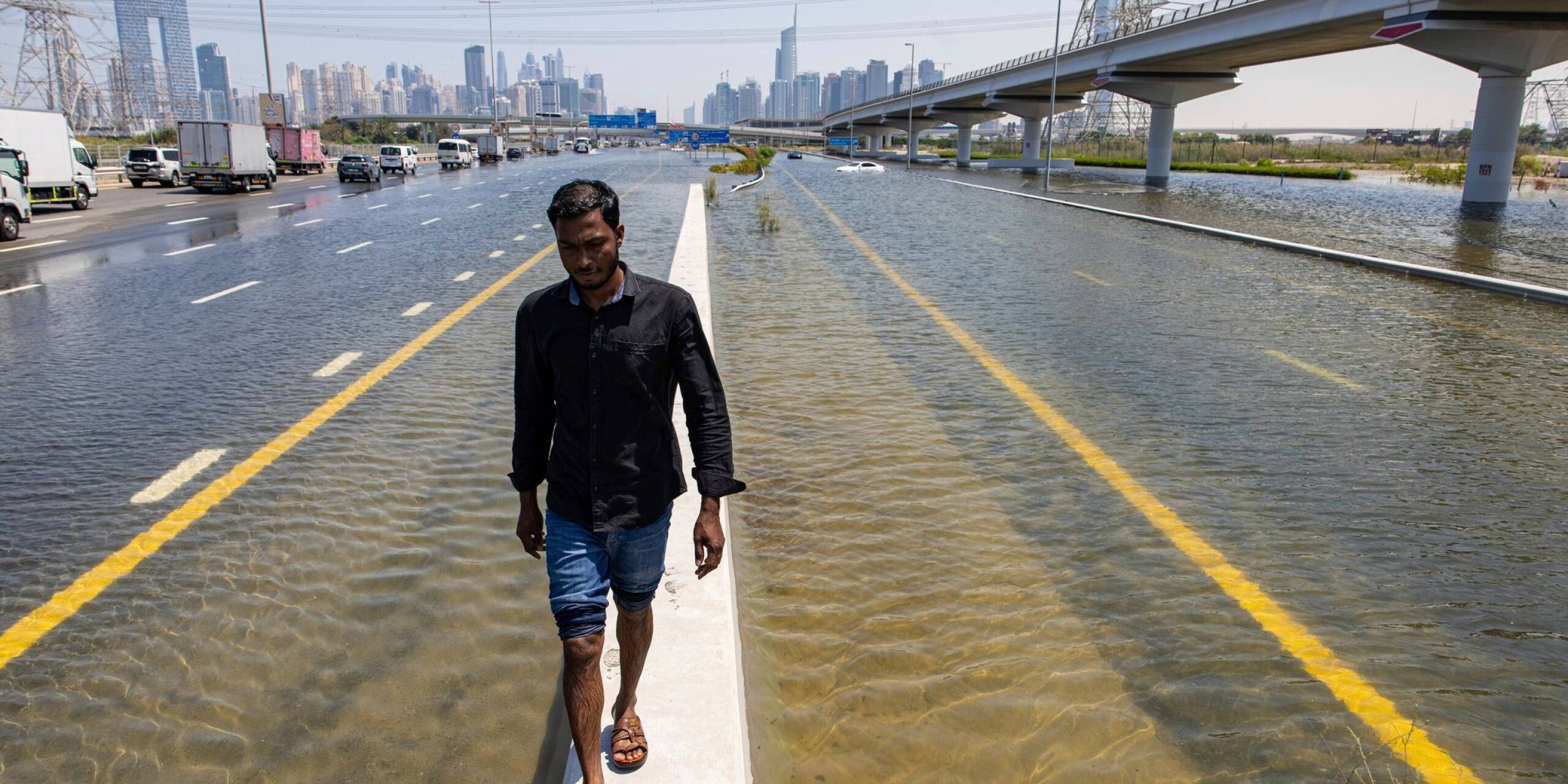In den Vereinigten Arabischen Emiraten hat sich der heftigste Regen seit Jahrzehnten ereignet und Teile der Metropole Dubai überschwemmt. Ein Mann geht entlang einer Straßensperre auf der Sheikh Zayed Road.