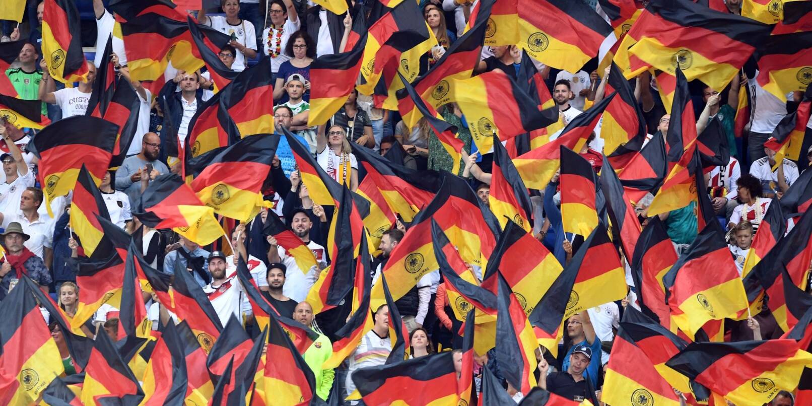Fans schwenken Deutschlandfahnen auf der Tribüne.