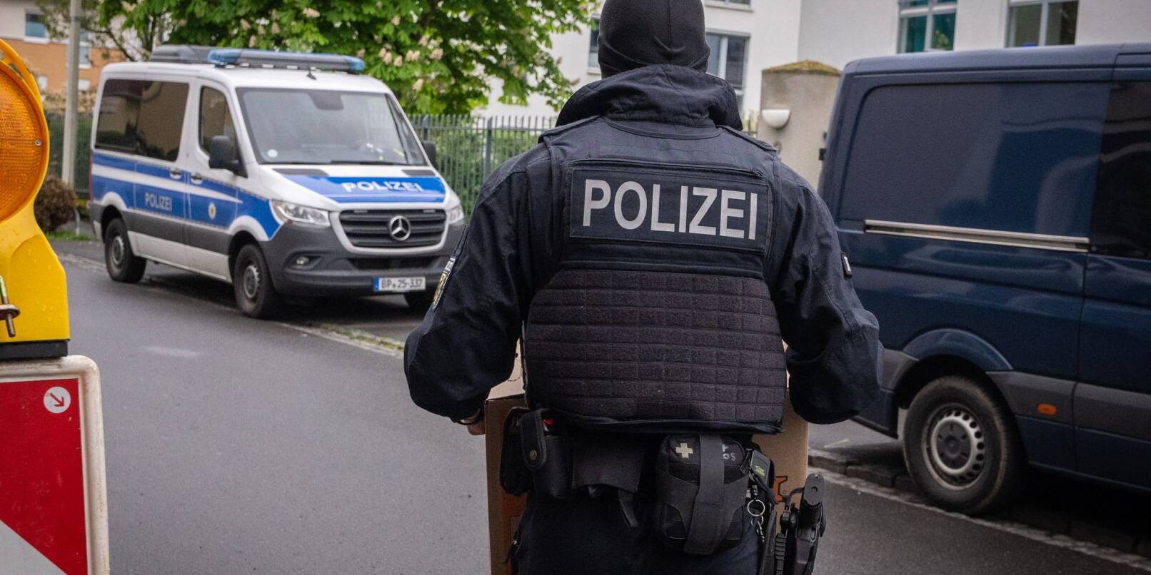 Ein Polizist trägt bei einem Einsatz in Bonn einen Karton mit beschlagnahmtem Material aus einem Gebäude.