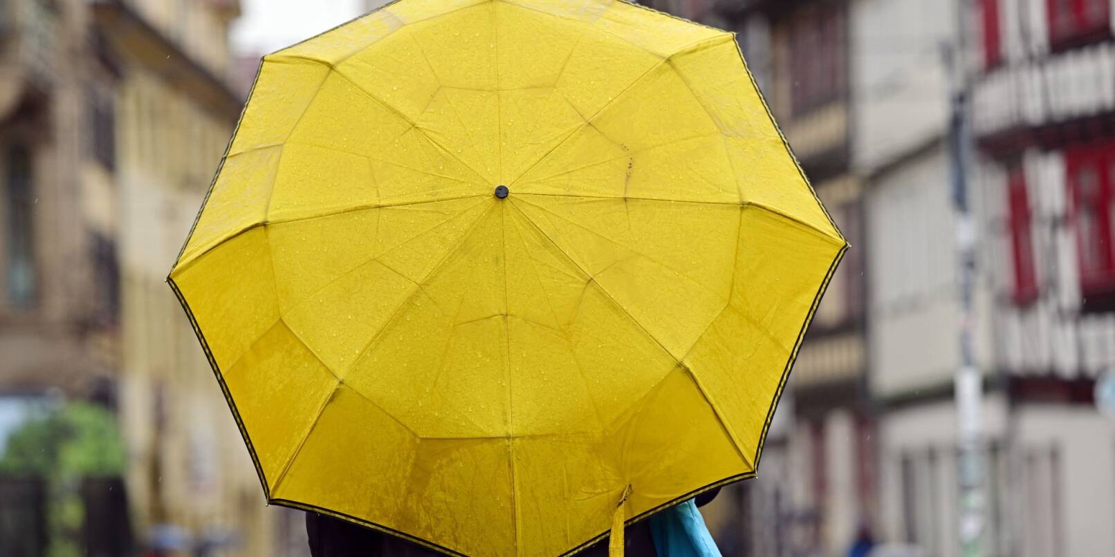 Eine Passantin mit gelbem Regenschirm.