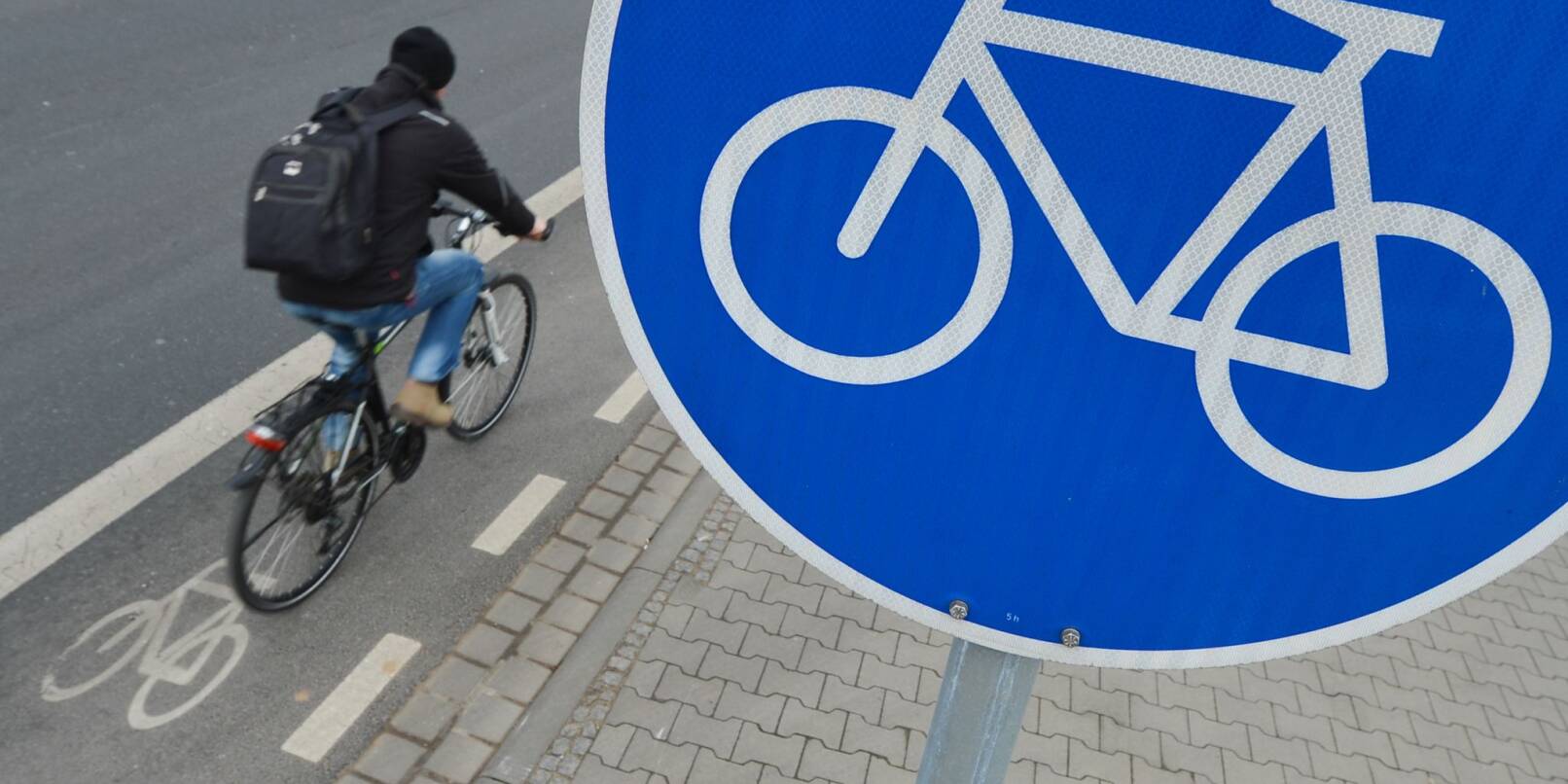 Ein Mann fährt mit seinem Fahrrad auf einem mit einem Verkehrsschild gekennzeichneten Radweg.