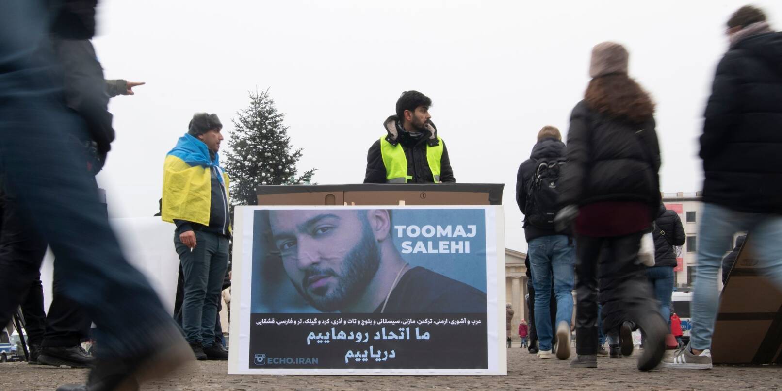 Protestaktion gegen Irans Staatsführung auf dem Pariser Platz in Berlin. Auf dem Plakat ist der Rapper Salehi zu sehen.