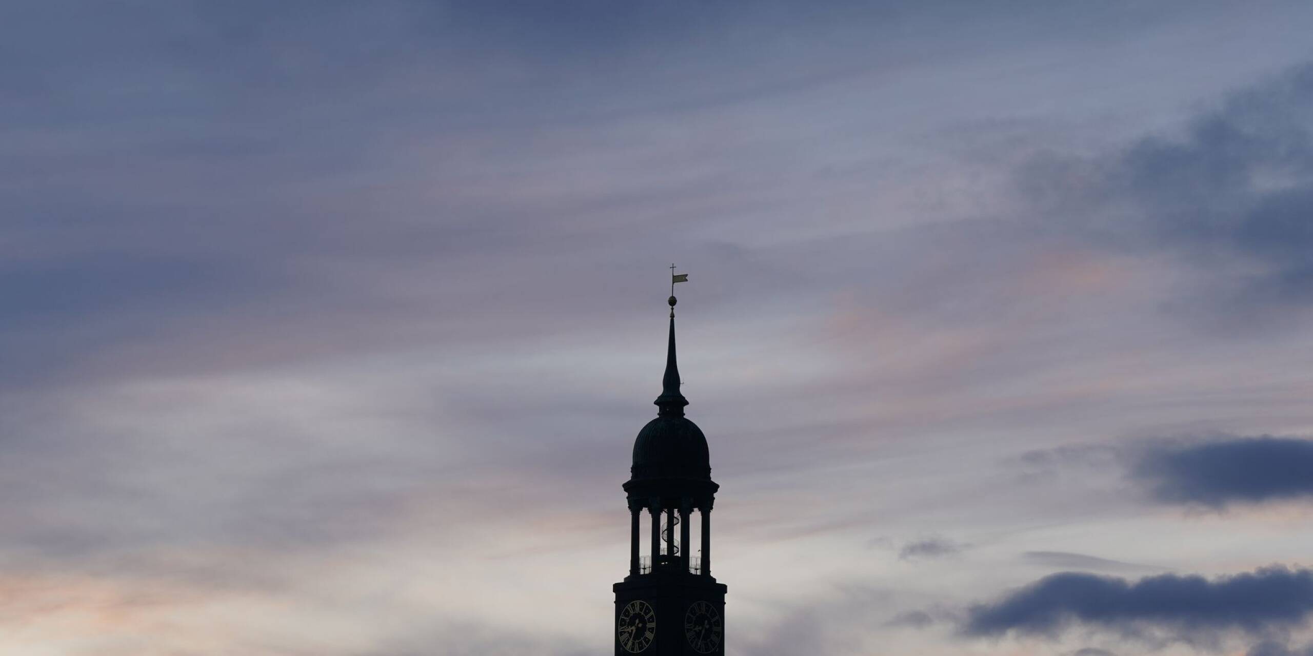 Die Turmspitze der Hamburger Hauptkirche Sankt Michaelis (Michel) ist vor dem abendlichen Himmel zu sehen.